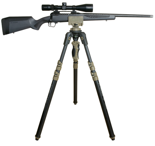 A black hunting rifle with a scope is mounted on a Primos Trigger Stick Apex Carbon Fiber Tripod against a white background.