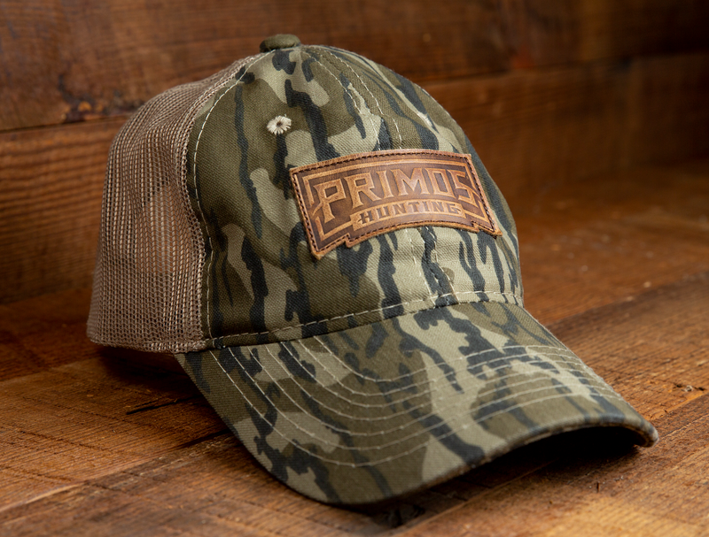 Load image into Gallery viewer, Primos Mossy Oak Original Bottomland Hat with logo patch, mesh back, shown on a wooden surface.
